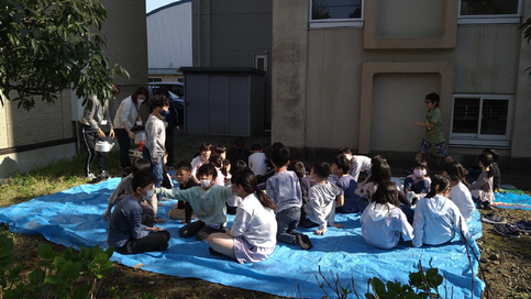 雷塚学童クラブの子供が外でおやつを食べている写真