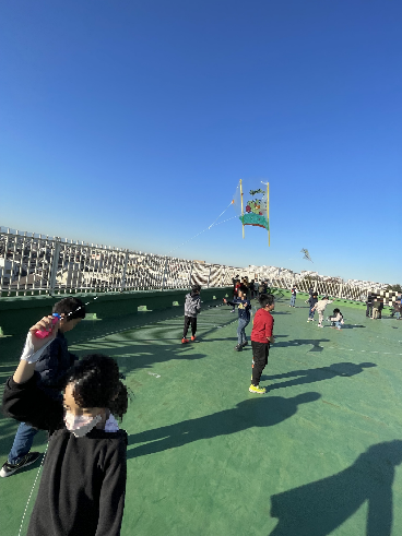 屋上で凧揚げをしている子供たちの写真